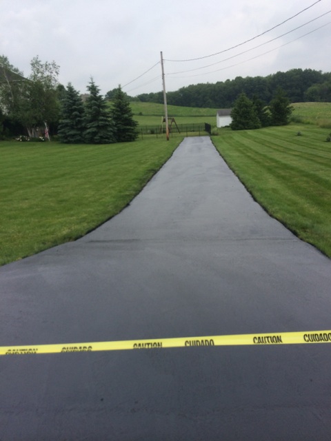 Long freshly paved driveway extending through rural Ohio property with green grass on both sides
